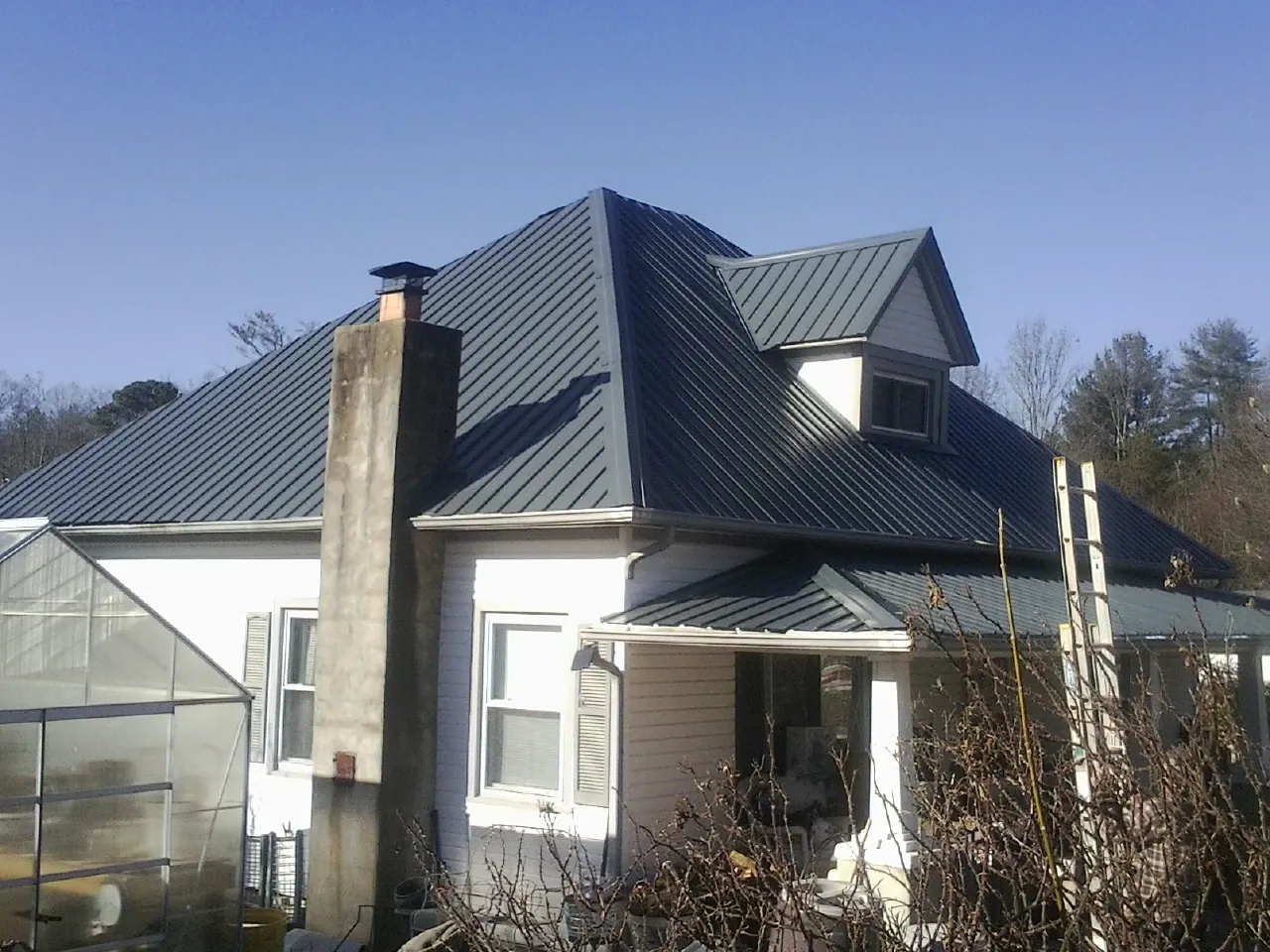 Dark blue standing seam metal roof on a white farmhouse with dormer — Slate & Tile Roof Repair by Roofing Brothers in Pray
