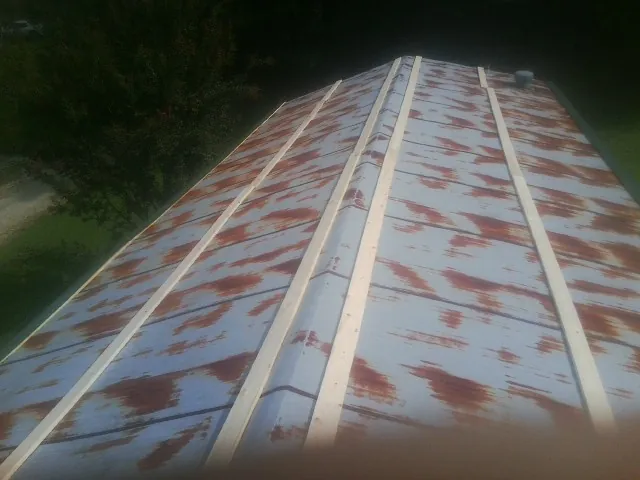 Rusted metal roof panels with new wood purlins before replacement — Storm Damage Roof Repair in Pray by Roofing Brothers