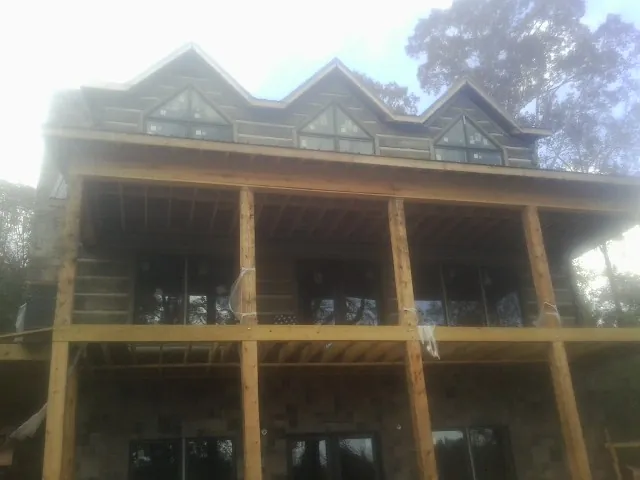 Dormers and porch framing on a large log home under construction — Roof Coating work by our crew in Pray