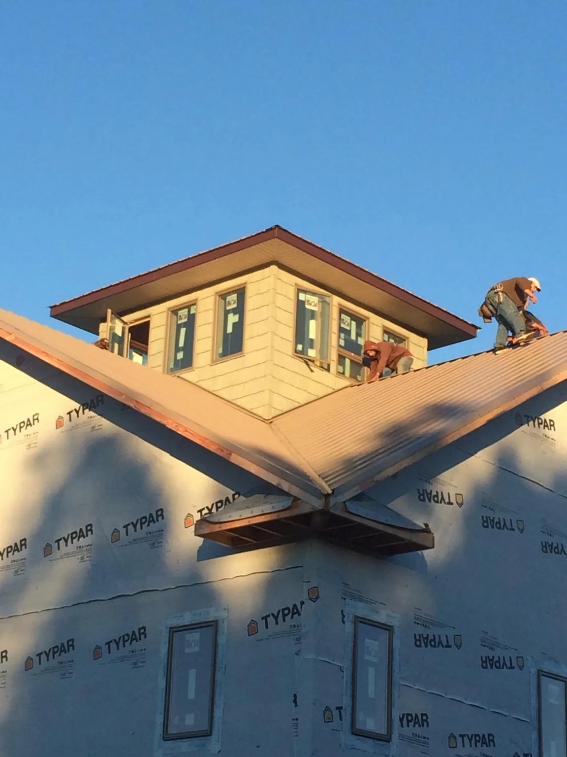 Roofers working around a rooftop cupola on a new metal roof at sunset — Roof Waterproofing in Pray by Roofing Brothers